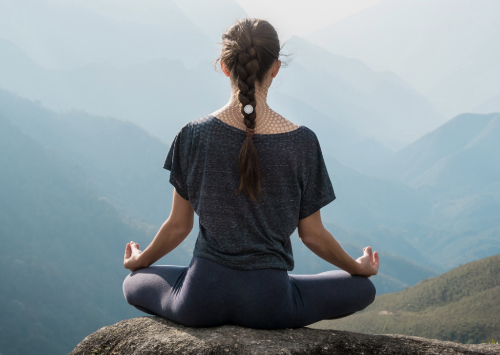 A woman practicing yoga in the mountains with LifeWave patch
